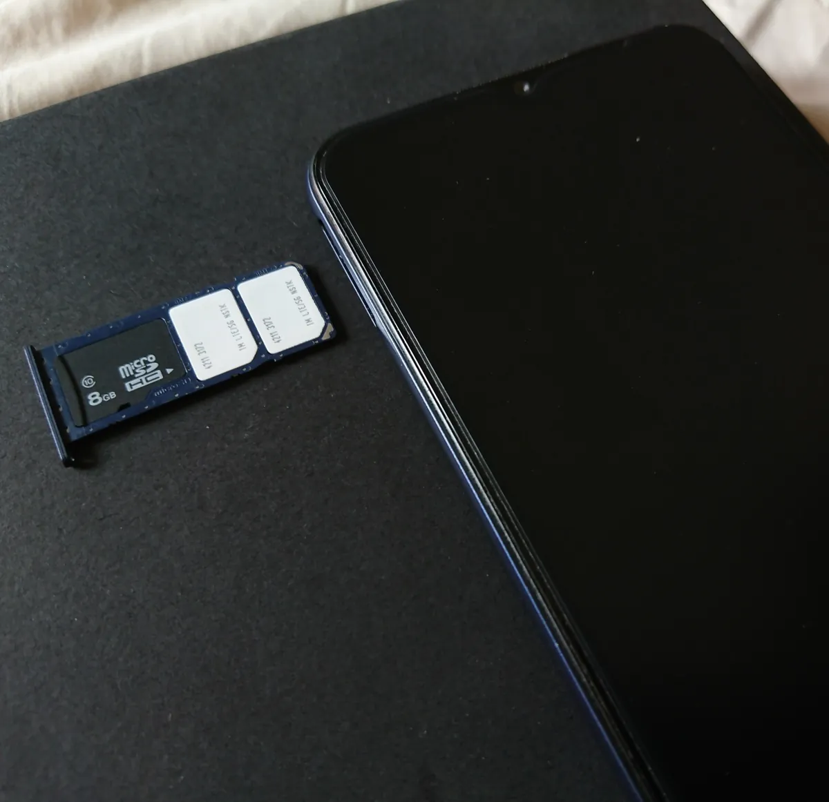 A smartphone with its SIM tray ejected showing two SIM cards and a microSD card